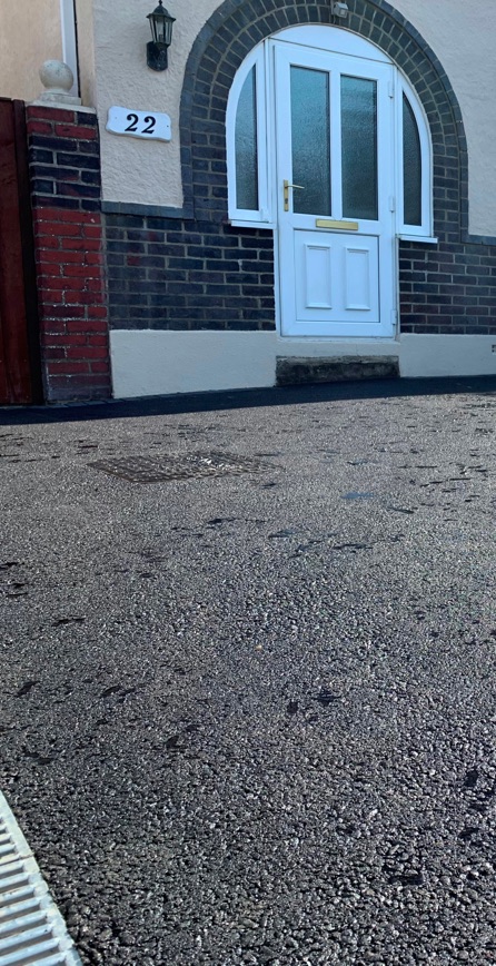 The front of a house with a new tarmac driveway.